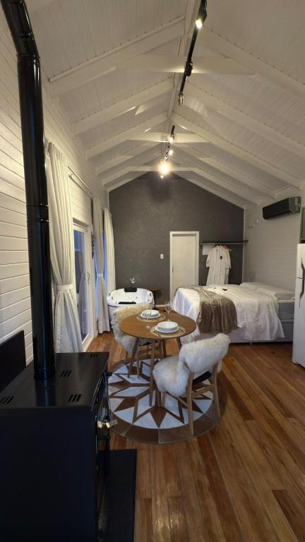 a room with a bed and a table and a room with a bedroom at Vila Chamonix - Chalé Carmenere in Urubici