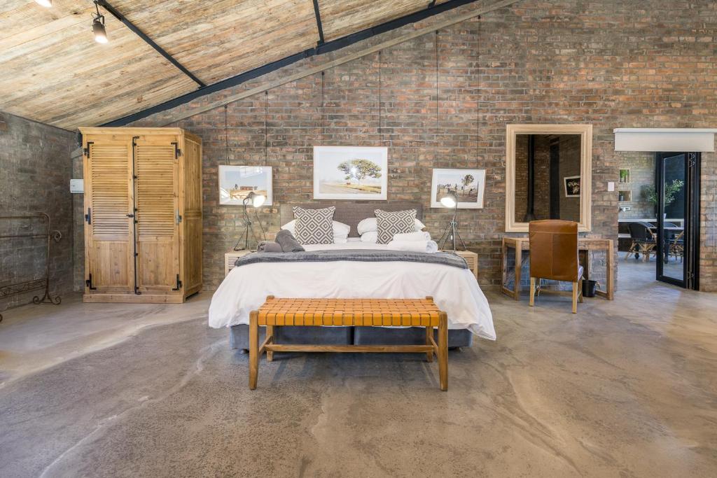 a bedroom with a bed and a brick wall at Avemore My Venue Le Verger in Onder-Papegaaiberg