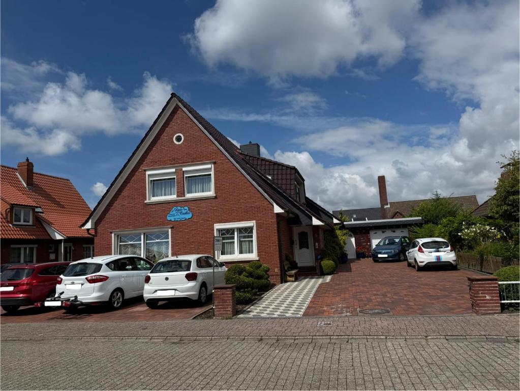 una casa con coches aparcados en un estacionamiento en Pension Cecilia, en Norddeich