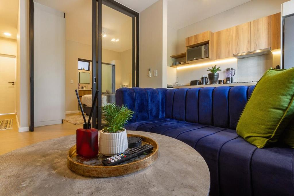 a living room with a blue couch and a table at #AlimamaSpaces The Rob's Akaru in Johannesburg