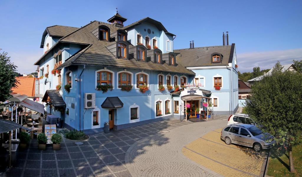 a blue building with a car parked in front of it at AGH Hotel in Rožnov pod Radhoštěm