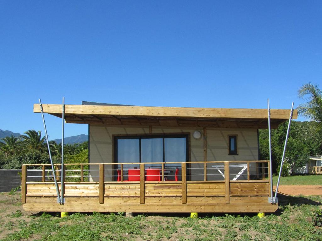 une petite maison avec un porche et une balançoire dans l'établissement Camping Miami plage, à Poggio-Mezzana