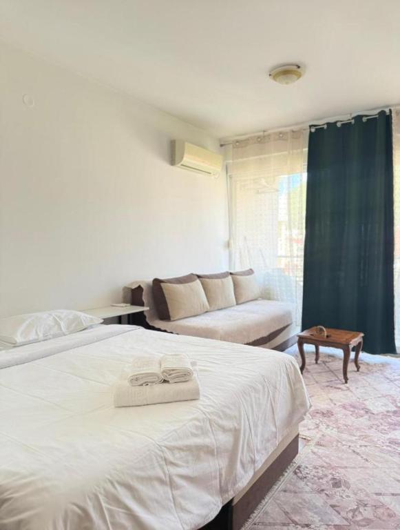 Un dormitorio con una gran cama blanca y un sofá. en Serenity Studio House, en Budva