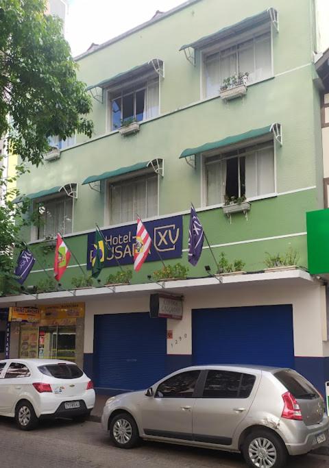 two cars parked in front of a building at Hotel Pousada XV in Blumenau