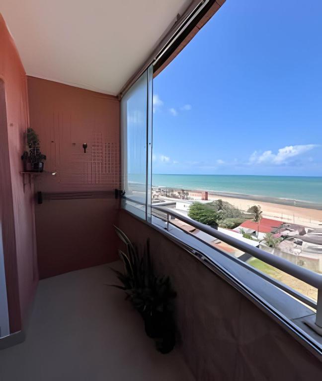 a room with a large window with a view of the beach at Flat à beira-mar com vista para a praia do meio in Natal