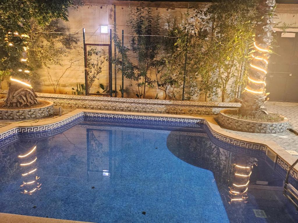 a swimming pool with lights next to a building at Villa bouisville ain el turk oran in Trouville