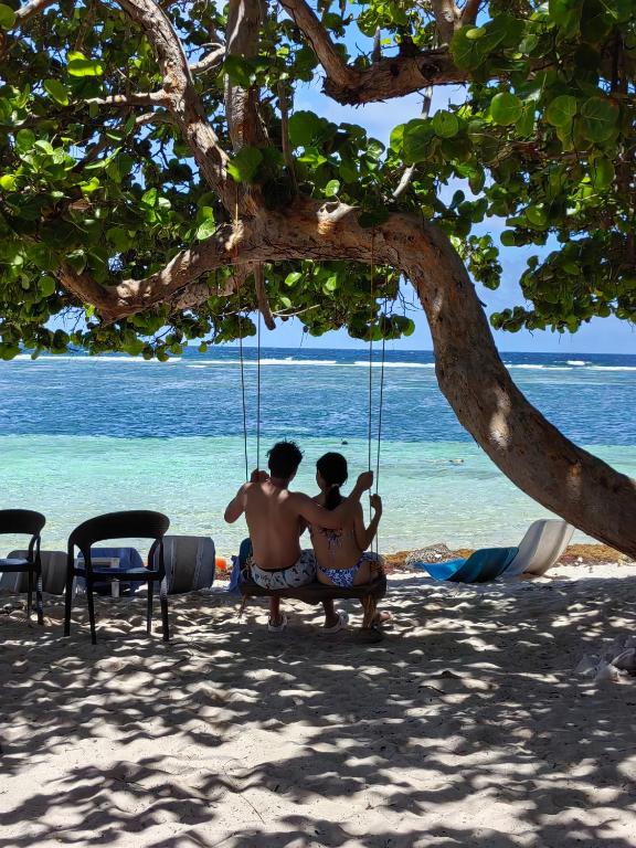 two people sitting in a swing on the beach at Hotel xahuayxol in Mahahual