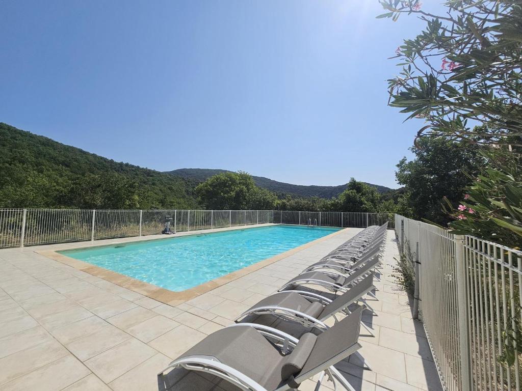 a row of lounge chairs next to a swimming pool at Oleandre in Cassagnolles