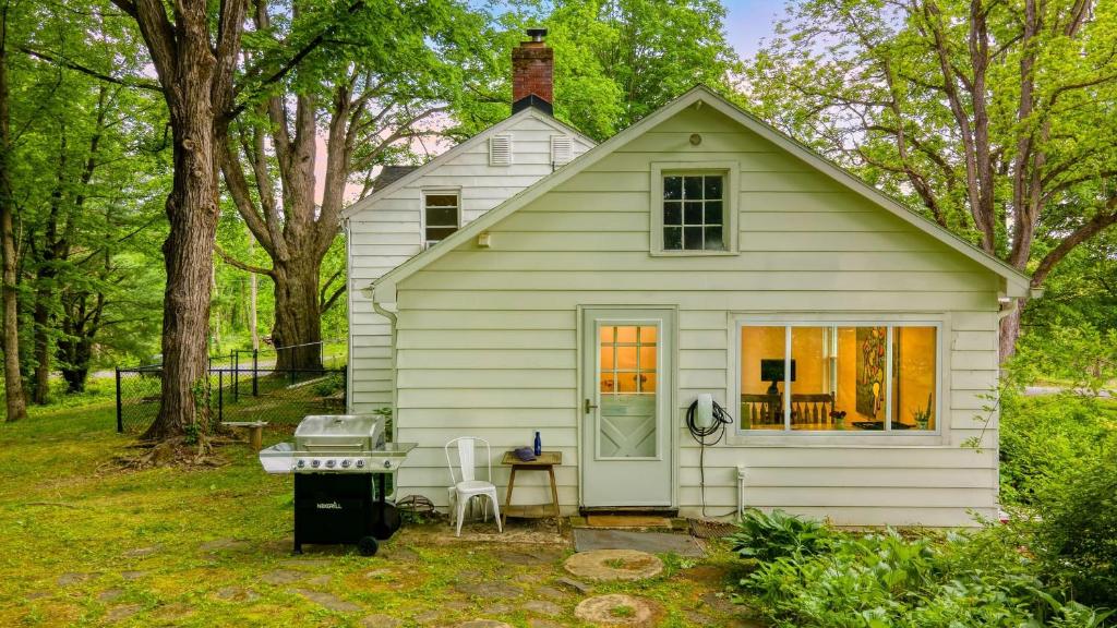 une petite maison blanche avec un barbecue dans la cour dans l'établissement Pondfront Gem Minutes from Hudson’s Best Shops Cafes The Stillwater House, à Hudson