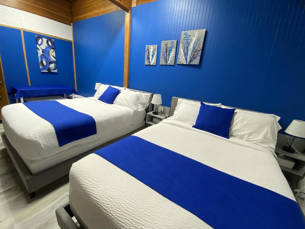 two beds in a room with blue walls at Motel Magistral in St-Raphael-de-Bellechasse