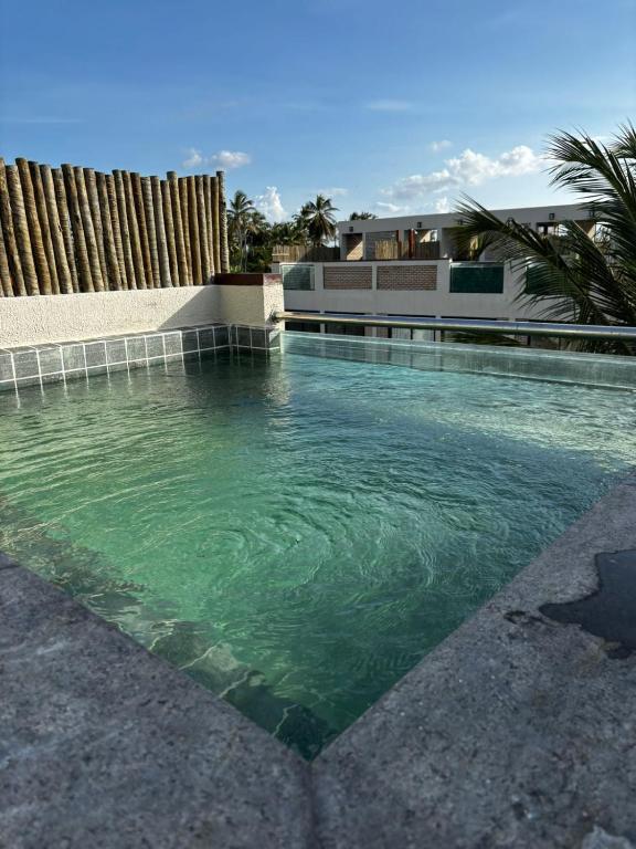 a swimming pool with green water in front of a house at Casa 12 do Paraíso - Atins in Atins
