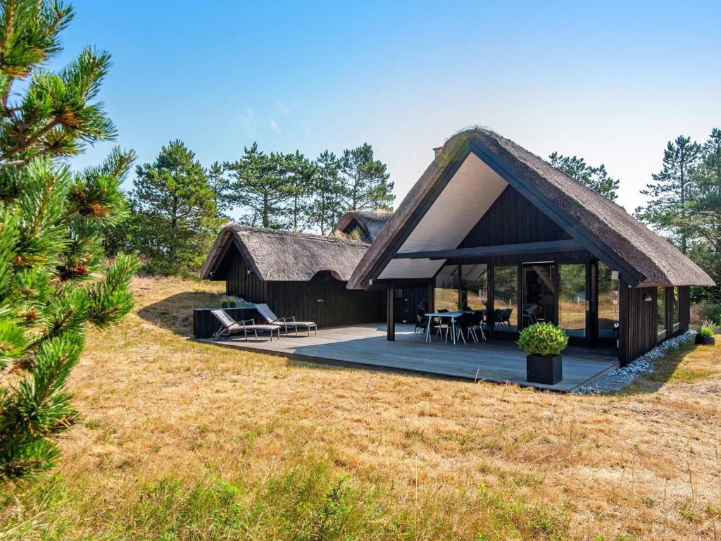 una capanna con il tetto di paglia su un campo di Luxury Retreat on Romo - By Traum Ferienwohnungen a Vesterhede