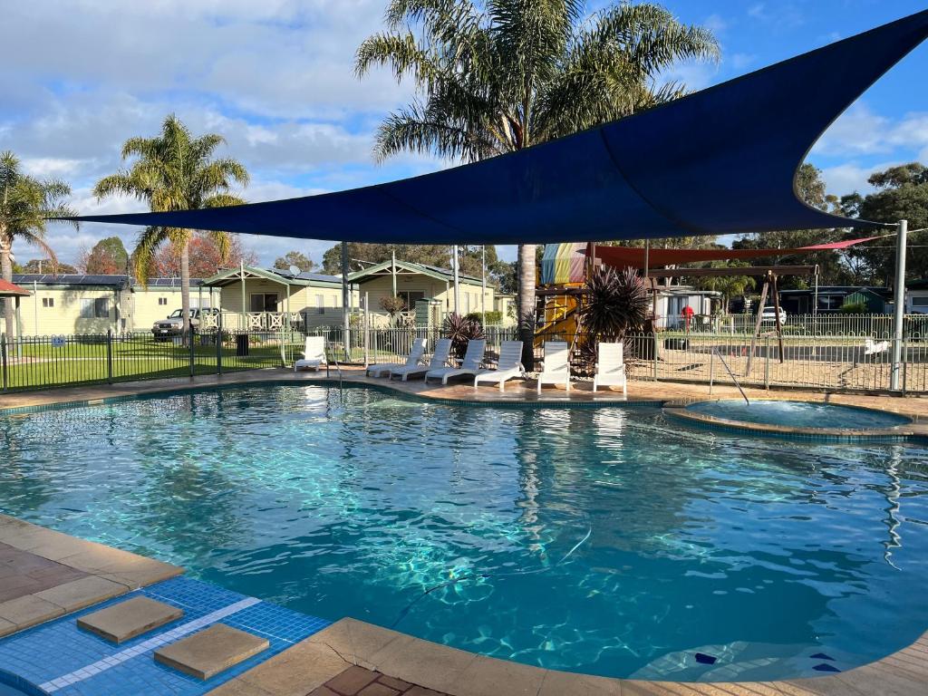 a swimming pool with a blue umbrella over it at Paynesville Holiday Park in Paynesville