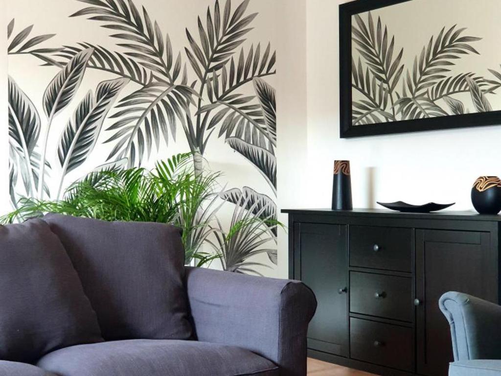 a living room with a couch and a plant at Charmant gîte 80m² proche frontière belge, jardin privatif, terrasse, tout inclus, 2 chambres, WiFi - FR-1-510-133 in Sebourg