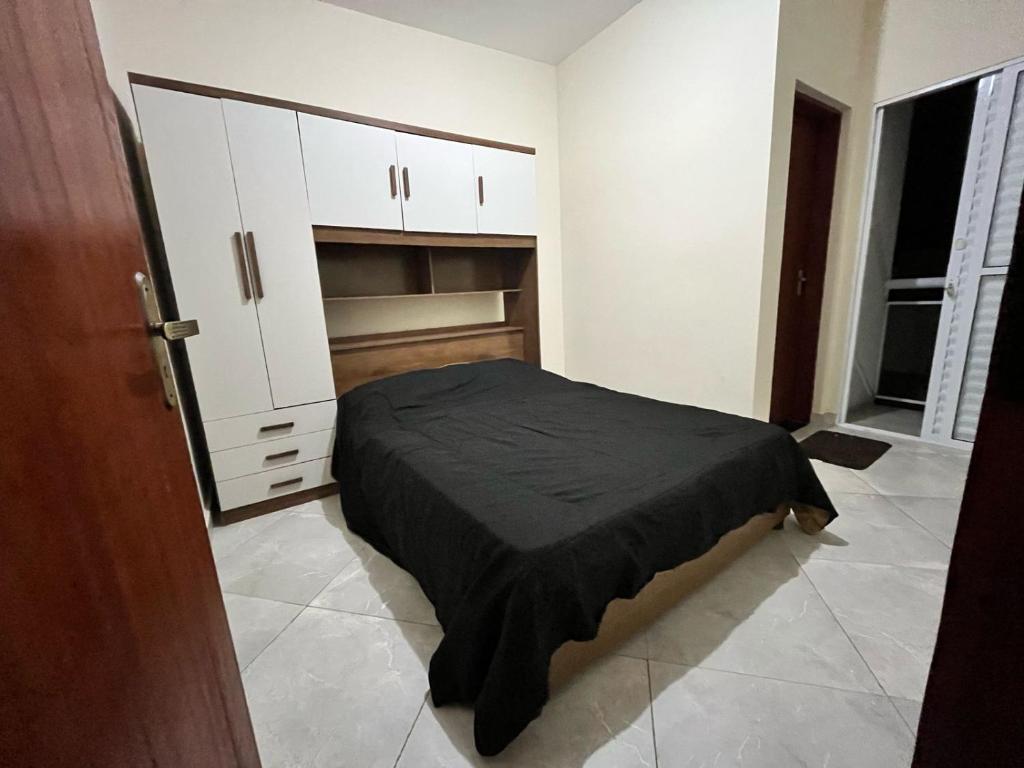 a small bedroom with a bed and white cabinets at Meu Encanto Itanhaém SP in Itanhaém