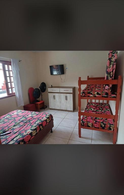a bedroom with two bunk beds and a television at Recanto da paz in Matinhos