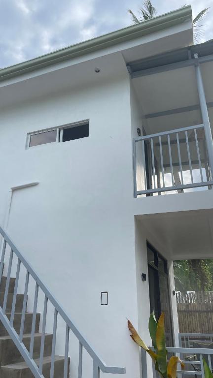 a white house with a staircase and a balcony at Padayon Island Stay in General Luna