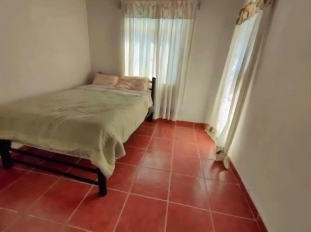 a bedroom with a bed and a red tile floor at Las mejores vacaciones en Paraíso Diamante in Gallinero