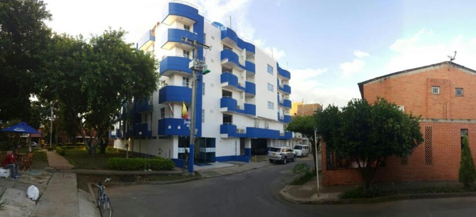 um edifício de apartamentos azul e branco numa rua em Aparta Hotel Jardines del Caney em Cali