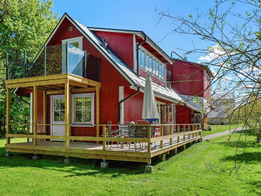 a red house with a deck and an umbrella at 4 person holiday home in Hemse in Hemse
