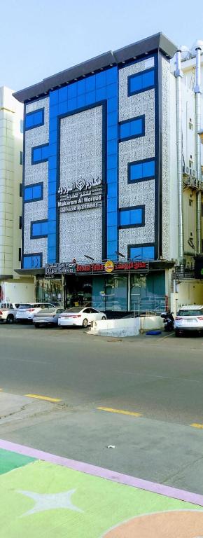 a blue and white building with cars parked in front of it at مكارم الورود للشقق المخدومة in Taif