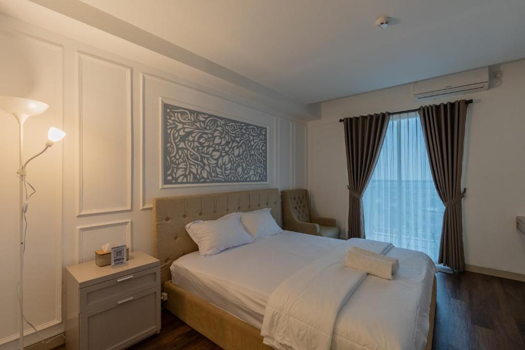 a bedroom with a bed and a window at Mataram City Apartment Urban View in Kejayan