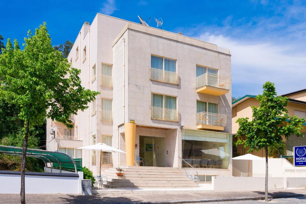 an apartment building with stairs in front of it at Hotel Caldelas in Caldelas