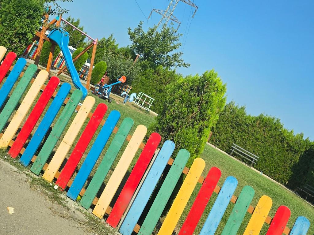 ein bunter Zaun in einem Park mit einer Achterbahn in der Unterkunft Coquette Appart in Eforie