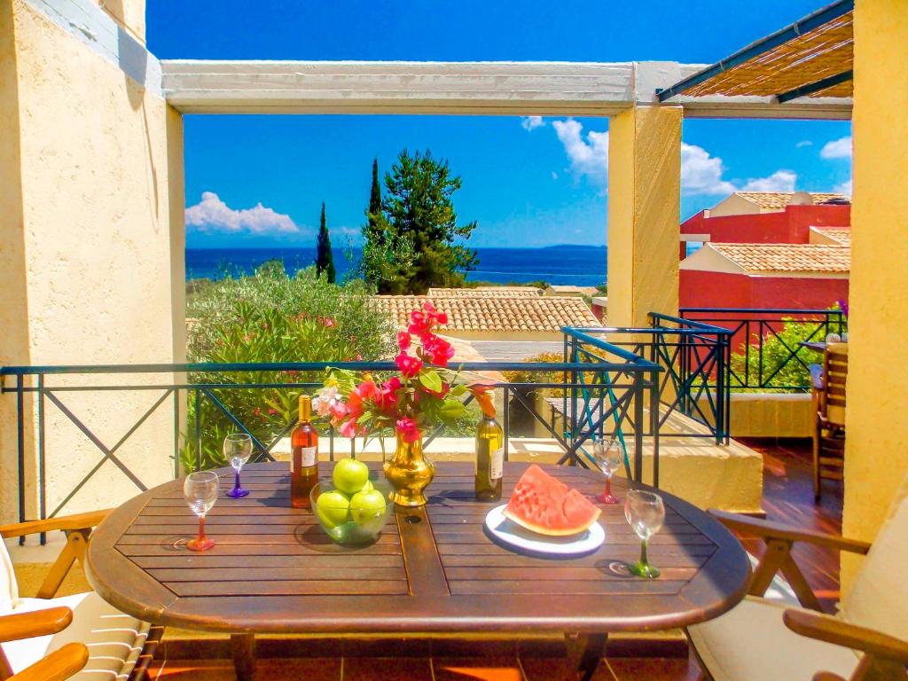 a table with a plate of fruit on a balcony at Manto On The Beach Apartments in Barbati