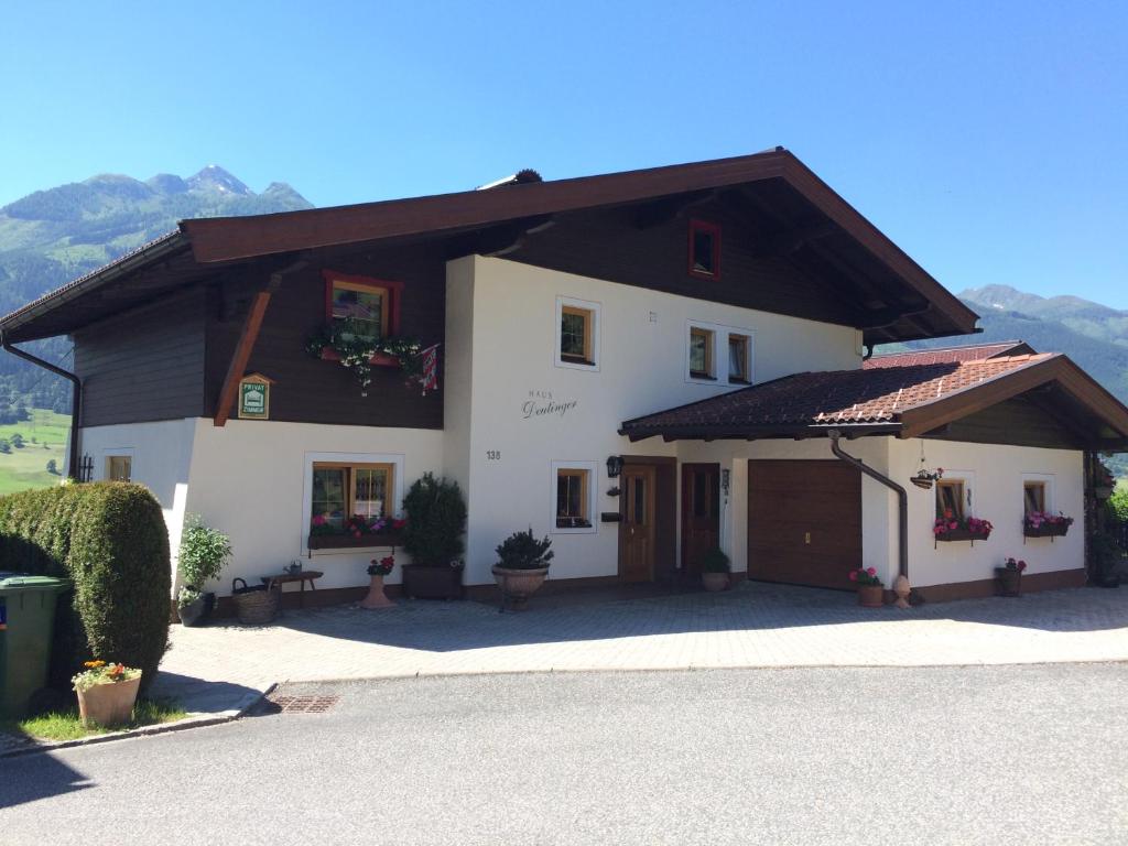 ein großes weißes Haus mit braunem Dach in der Unterkunft Haus Deutinger in Piesendorf