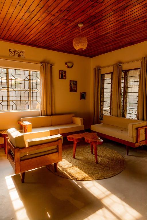 a living room with couches and tables and windows at Arusha backpackers homes in Arusha