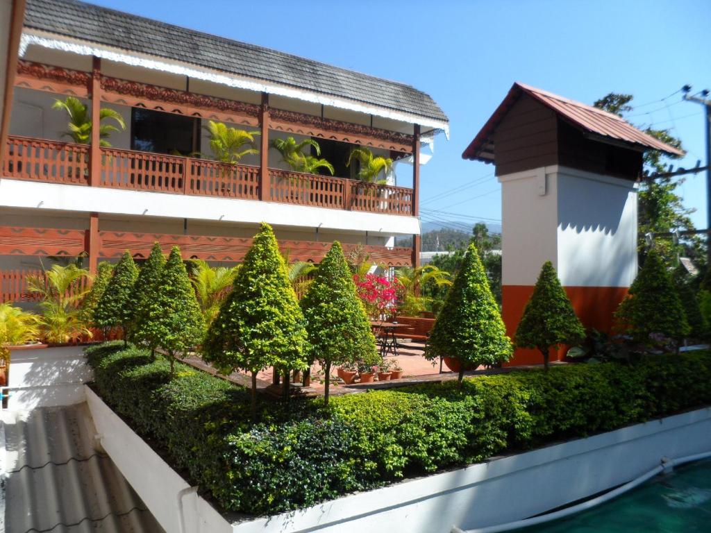 a garden in front of a building with trees at Baiyoke Chalet Hotel in Mae Hong Son
