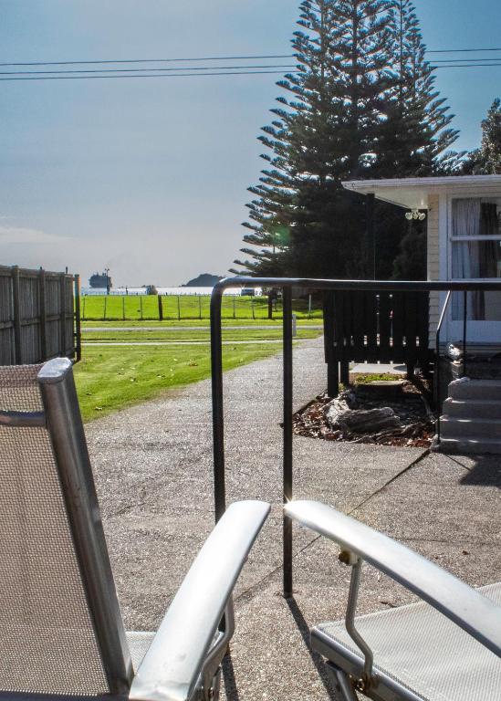 a porch with a chair and a bench and grass at Waitangi Beach Unit B in Paihia