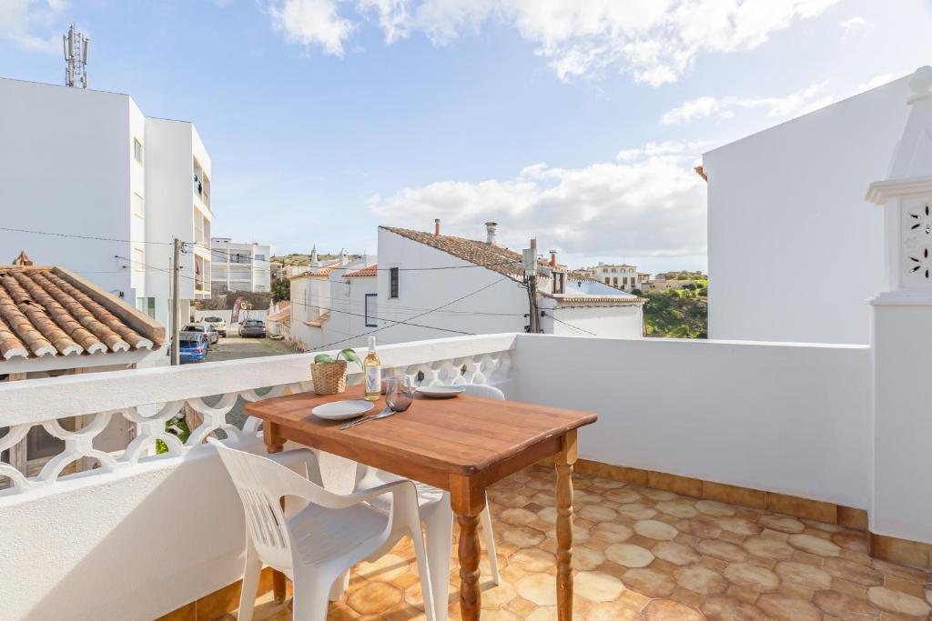 a balcony with a wooden table and white chairs at Blue House Burgau in Burgau
