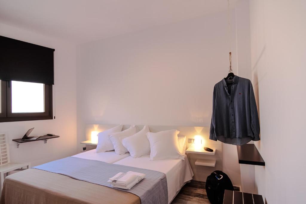 1 dormitorio con 1 cama con chaqueta negra colgada en la pared en The 8 Rooms House, en Tarifa