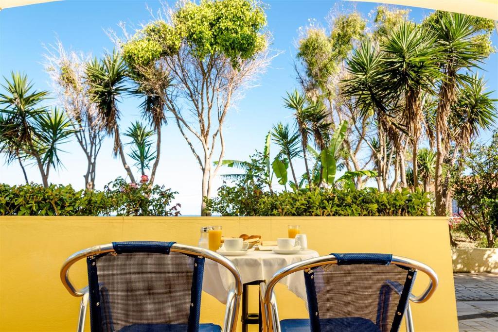 a table and chairs on a balcony with palm trees at Ammes Hotel in Svoronata