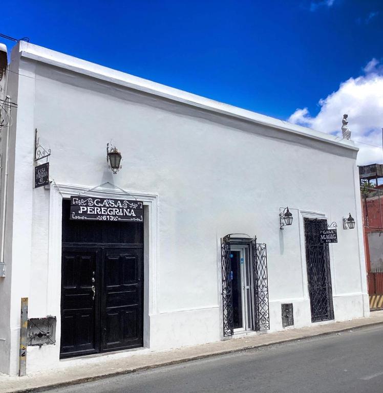 a white building with a black door on a street at Casa Peregrina 613 in Mérida