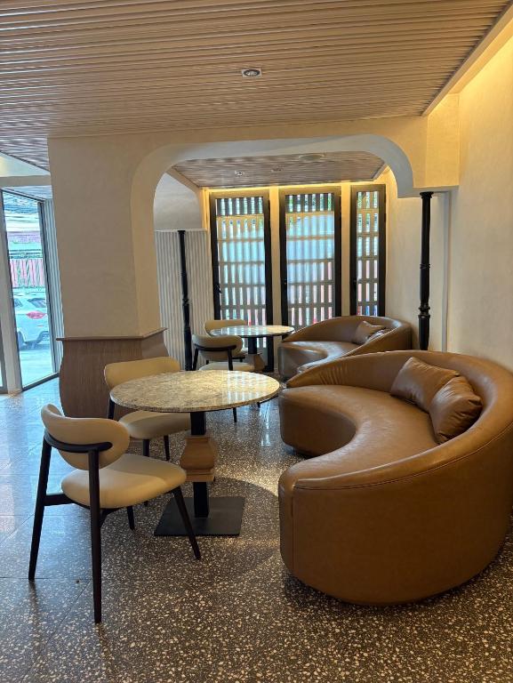 A compact hotel lounge with curved leather seating and small marble-topped tables.