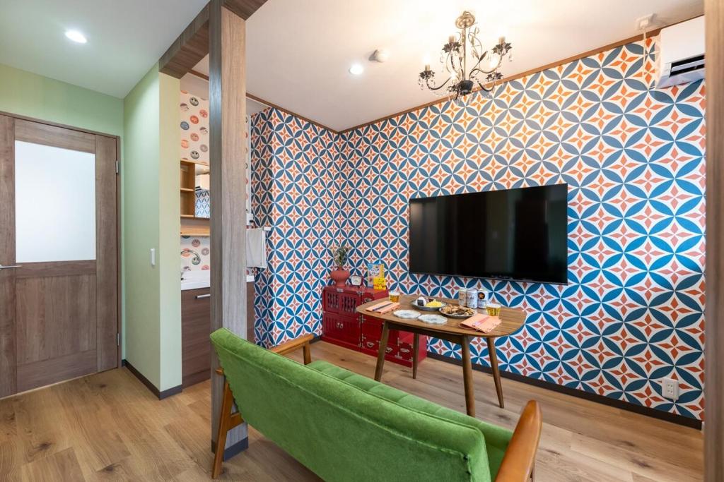 a living room with a table and a tv on a wall at 長期ステイ歓迎 ポップ ディズニー風 TDR スカイツリー好アクセス 定員3名 東京駅10分 駐車場予約 送迎有 HOTEL DREAM MUSIC Tōyōchō japanese-pop in Tokyo