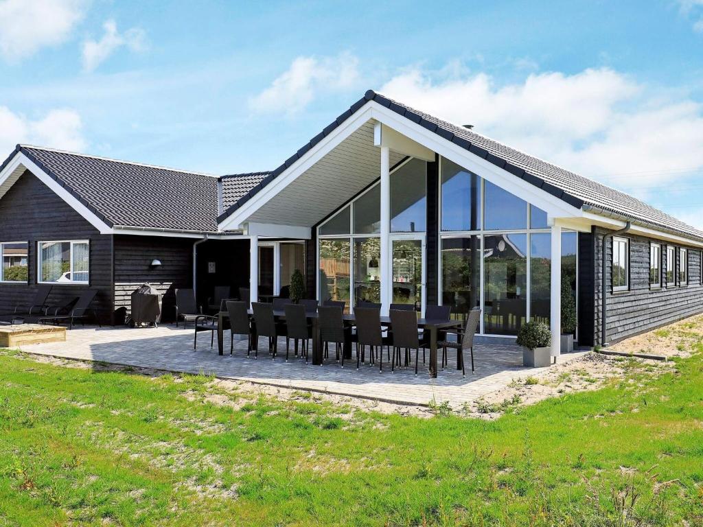 a house with glass doors and tables on a patio at 18 person holiday home in Ringkøbing in Ringkøbing