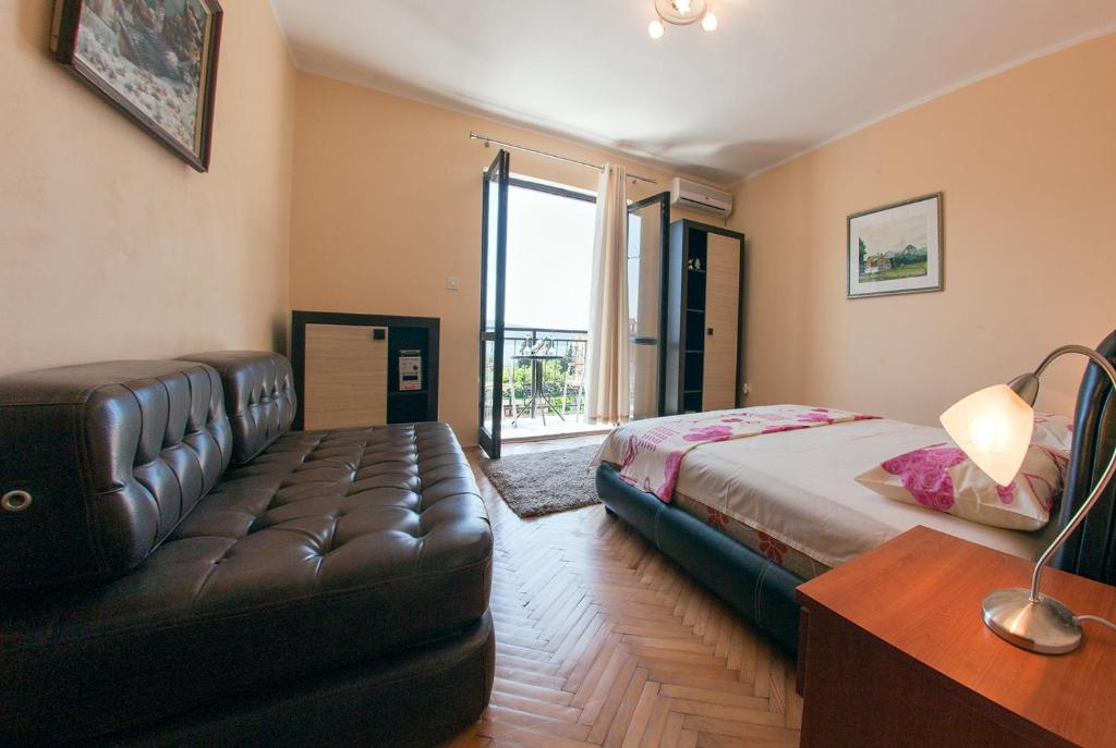 um quarto com uma cama e um sofá de couro em Apartments Lena em Herceg Novi