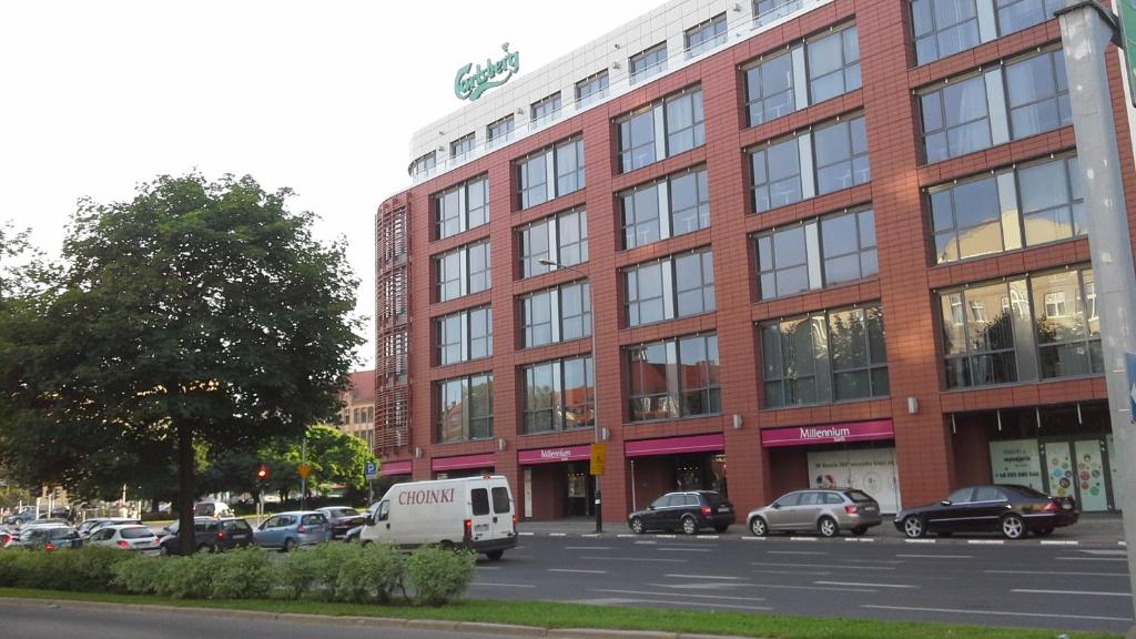 a large brick building with cars parked in a parking lot at Centrum Stary Rynek Poznań in Poznań