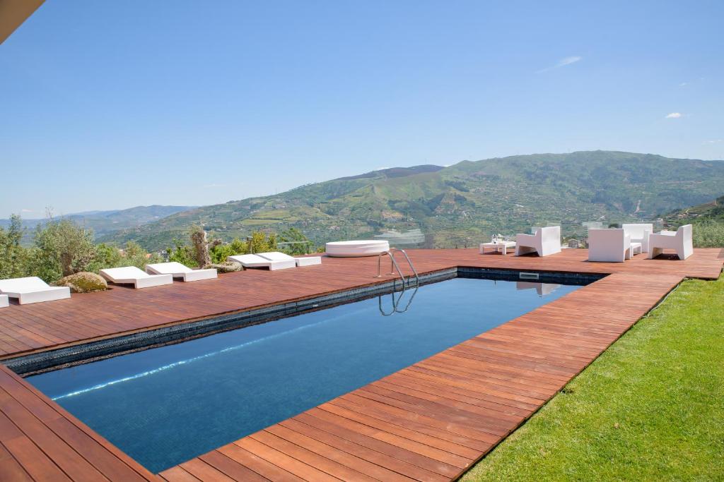 uma piscina com espreguiçadeiras e cadeiras de madeira e uma montanha em Quinta Do Bosque em Mesão Frio