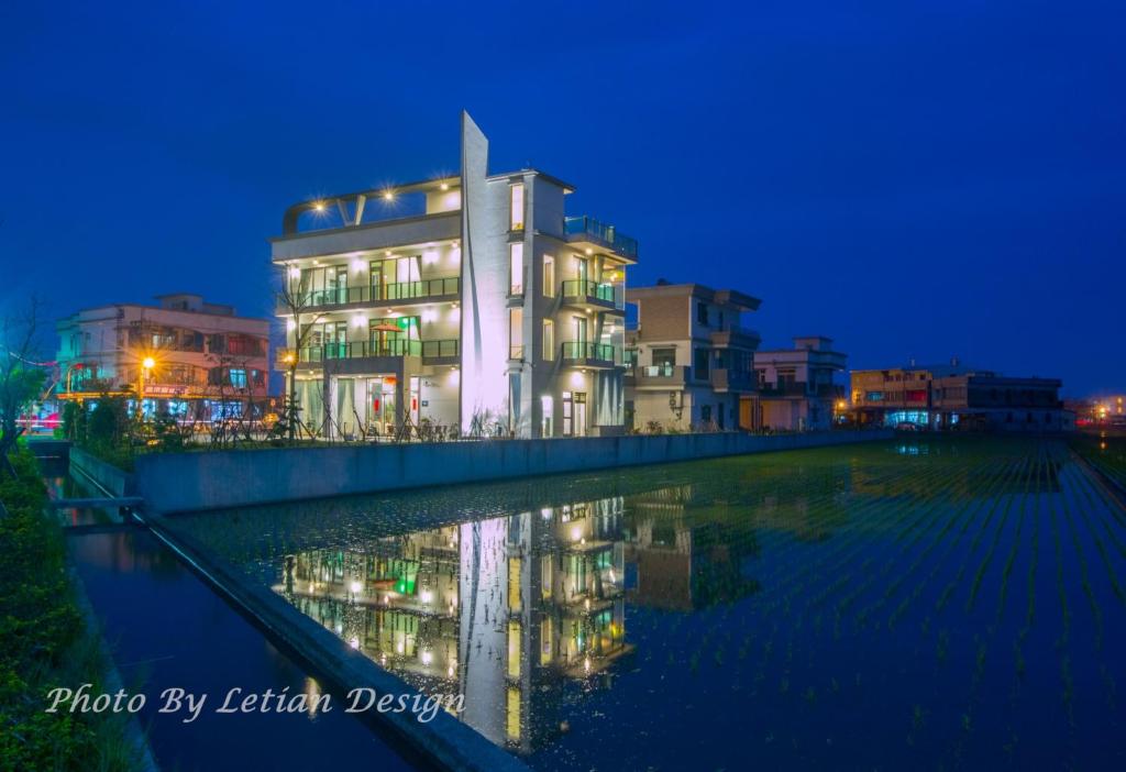 un edificio junto a un cuerpo de agua por la noche en Colorful Fish Cottage, en Zhuangwei