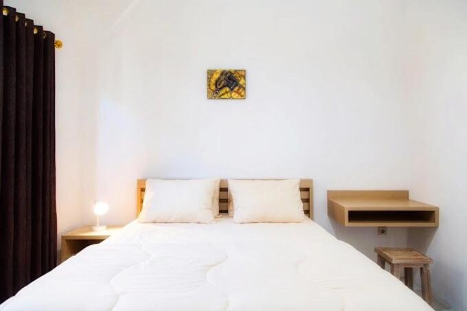 a bedroom with a large white bed with two pillows at Uluwatu Hill House in Uluwatu