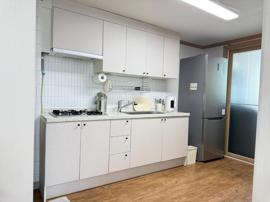 Una cocina blanca con fregadero y refrigerador. en Magnolia Wonju branch, en Wonju