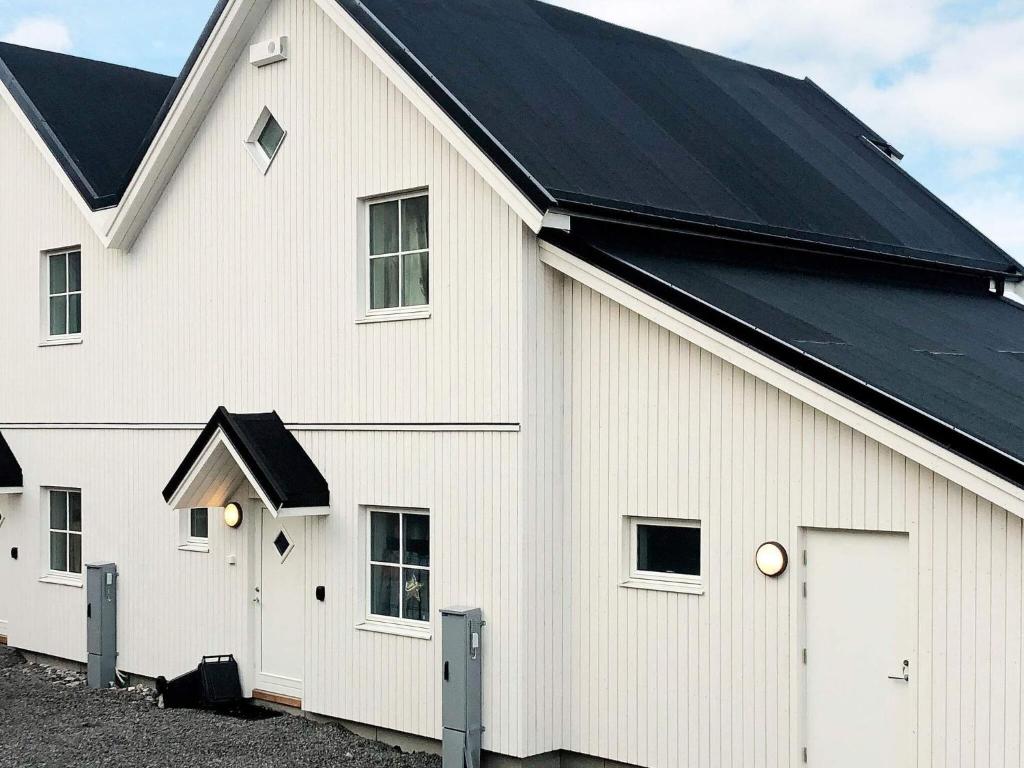 a white barn with a black roof at 6 person holiday home in Kverva in Dyrvik