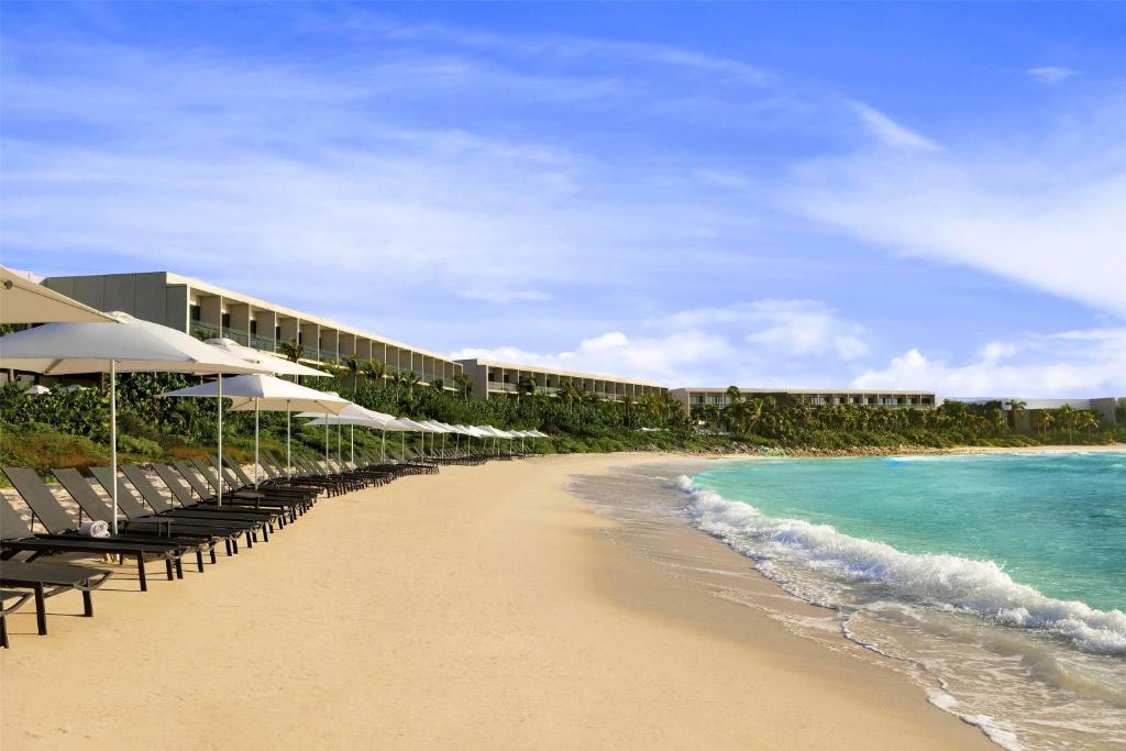 a beach with chairs and umbrellas and the ocean at Hilton Tulum Riviera Maya All-Inclusive Resort in Tulum