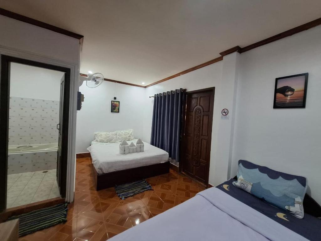 ein kleines Zimmer mit zwei Betten und einem Spiegel in der Unterkunft Sichaluenkham vangvieng HOTEL in Vang Vieng