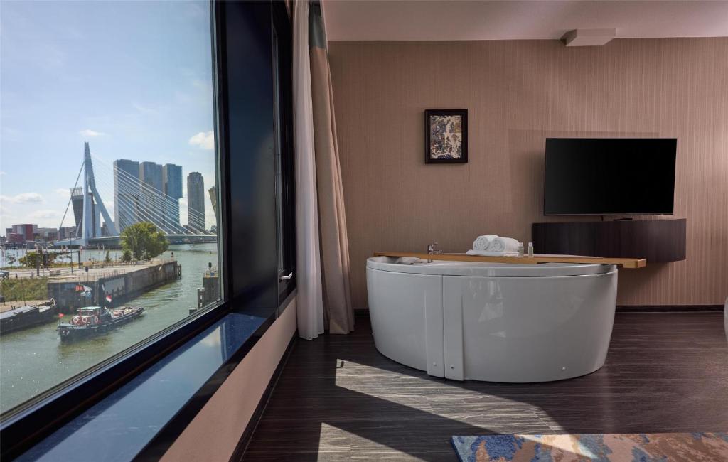 a bath tub in a room with a large window at Haven Hotel Rotterdam, Curio Collection by Hilton in Rotterdam